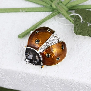 Macro view of ladybug brooch with amber crystals and black enamel details on white texture