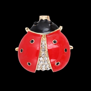 Macro shot of ladybug brooch with red enamel and sparkling white rhinestones on black