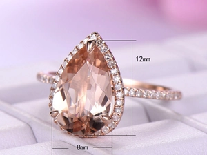 Macro shot of pear-cut pink gemstone ring in rose gold with halo diamond setting