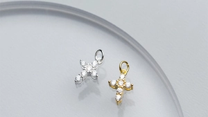 Detail of silver and gold cross pendants with zircons on a textured background