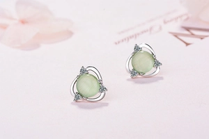 Macro shot of silver floral stud earring with green cat-eye stone and white cubic zirconia