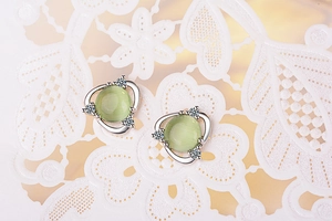 Detail of flower cat-eye stone stud earring with zircon accents on white lace background
