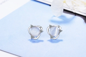 Macro detail of cat eye stone stud earring with silver setting and zircon floral accent