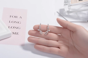 Hand-held close-up showing micro-set zircon details on silver stud earrings
