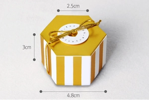 Detalle de una mini caja de regalo hexagonal con rayas amarillas y un lazo dorado