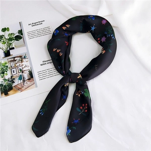 Close-up of black silk scarf with colorful floral and star patterns on white background