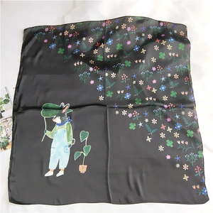 Detail of a black satin square scarf featuring floral prints and a cute rabbit character