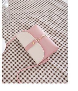 Detail view of pink and beige PU leather crossbody bag with golden deer charm