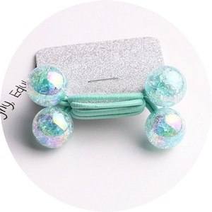 Detail of green elastic hair ties featuring glittery transparent resin beads on a silver card
