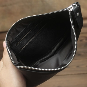 Close-up of black leather pouch with silver zipper and interior card slot compartment