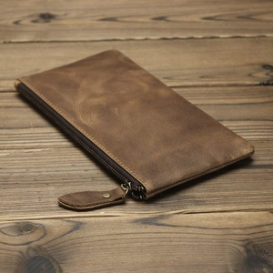 Close-up of vintage brown crazy horse leather pencil case with zipper on wood background