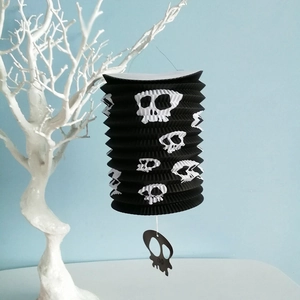Gedetailleerd overzicht van zwarte Halloween papieren vouwlantaarn met witte schedels, decor.