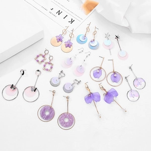 Flat lay of purple crystal and resin earrings set on an artistic fashion magazine