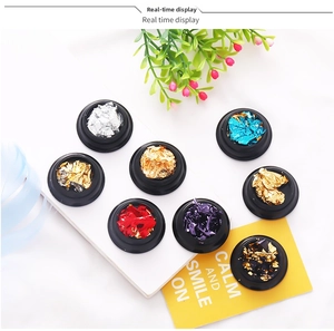 Detail van 8 kleuren nail art folievlokken in ronde potjes op wit marmer