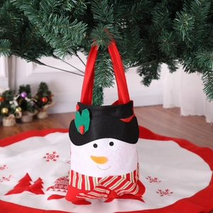 Detail of a snowman non-woven Christmas gift bag hanging on a festive holiday tree