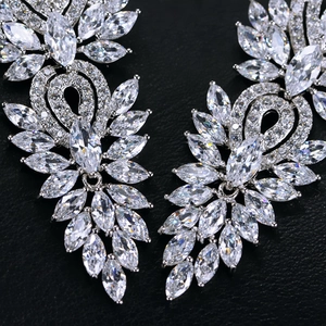 Gros plan de boucles d'oreilles argentées avec zircones AAA marquise sur fond texturé noir