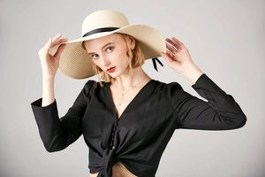 Detailed weave texture of summer straw hat with a black bow ribbon on a model