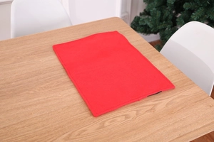 Detail of red rectangular Christmas place mat with stitched edges on a wooden dining table