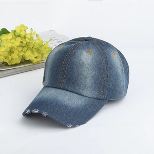 Detailed macro view of vintage washed blue denim baseball cap with orange stitching and distressed edges