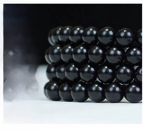 Macro shot of 108 polished black ebony beads showing natural wood grain and texture