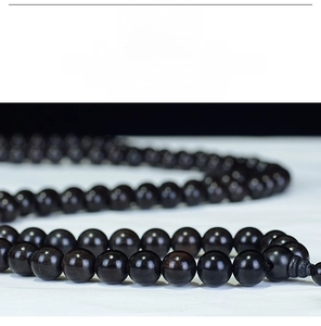 Macro shot of 108 polished ebony wood beads showing dark oily texture and fine grain
