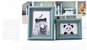 Detail of vintage blue picture frames with gold trim and animal art on a tabletop