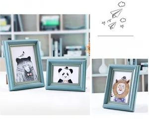 Detail view of retro blue picture frames with gold beaded edges and hand-drawn animal art