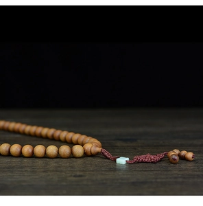 Macro shot of natural sandalwood prayer beads with vintage wood texture and jade accents