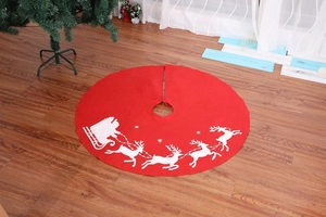Detail of red Christmas tree skirt with white reindeer and Santa Claus sleigh pattern