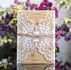 Detail showing laser-cut lace sleeve and kraft paper wedding invitation with twine knot