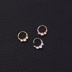 Detail view of gold, silver, and rose gold tribal septum rings with zircon on black leather