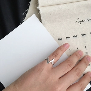 Close-up of minimalist heartbeat wavy ring worn on hand with April calendar background