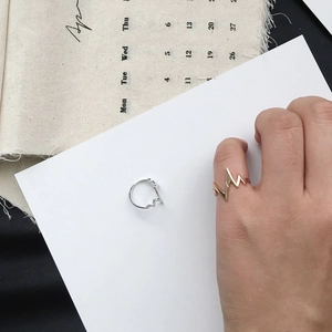 Detailed view of minimalist gold and silver heartbeat pulse rings on a stylish background