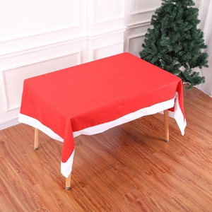 Close-up of red and white Christmas tablecloth set on a wooden dining table