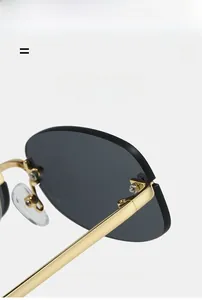 Detail of Y2K rimless sunglasses showing golden metal hinges and lightweight grey lenses