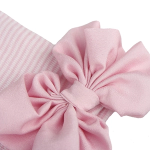 Detailed shot of baby beanie featuring pink striped knit fabric and a large chiffon bow