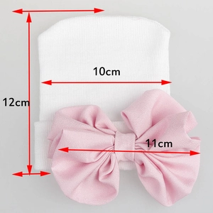 White newborn knitted baby hat featuring a large pink chiffon bow with size measurements
