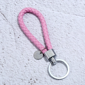 Close-up of pink braided leather keychain with silver metal ring and blank tag