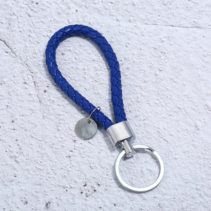 Detail of hand-woven dark blue leather keychain with silver metal ring and engravable tag