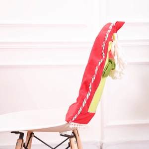 Side view of festive red velvet Christmas chair cover featuring Santa design on a white chair