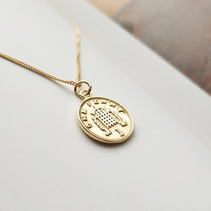 Detailed macro view of a 925 sterling silver gold penny coin pendant on a fine O-chain