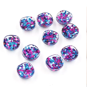 Flat lay of 10 clear resin round charms with blue and magenta hexagonal sequins inside
