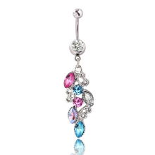 Detailed view of silver belly ring with pink and blue rhinestones on white background