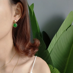 Elegant green agate stud earring on model with gold necklace and leafy background