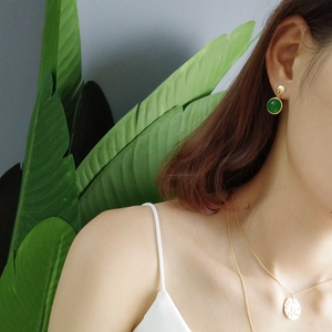 Close-up of S925 silver gold-plated green agate earrings and vintage coin necklace on model