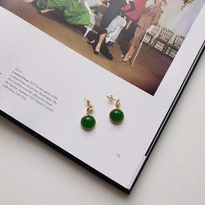 Vintage green agate studs in gold plated setting placed on a retro fashion magazine