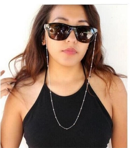Silver beaded metal eyewear chain accessory shown on a model wearing sunglasses
