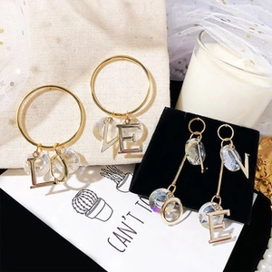 Detail view of gold LOVE earrings with crystal beads on soft beige and velvet display