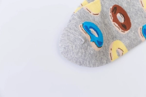 Detail of gray cotton sock toe with colorful doughnut patterns on white background