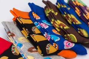 Pile of colorful cotton socks with vibrant food patterns like donuts, pizza, and avocado